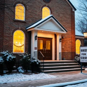 Warm lights shining from a church during winter indicating a cold weather shelter.